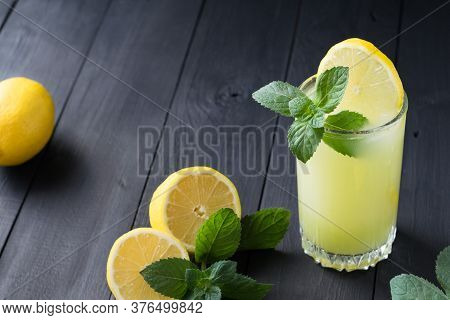 A Glass Of Lemonade With Slice Of Lemon And Mint, Cold Refreshing Drink Or Beverage With Ice On Dark