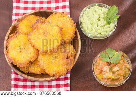 Patacón Fried Pieces Of Crushed Green Banana. Guacamole. On The Wooden Table (tostón, Tachino)