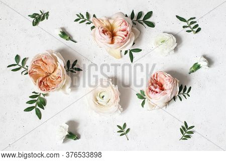 Floral Composition With Pink English Roses, Ranunculus And Green Leaves On White Concrete Table Back