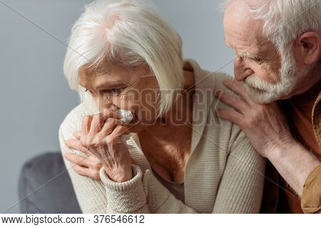 Senior Man Touching Shoulder Of Crying Wife Holding Paper Napkin