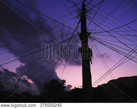 Electric Pole With Many Wires In The Evening Sky