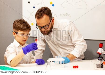 Dad And Son Play With A Microscope In A Makeshift Laboratory