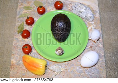 On A Green Plate Avocado, Garlic And Around: Vegetables, Chicken Eggs, Seashells, Cherry Tomatoes, S
