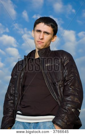 Jeune homme cherche à vous contre le ciel bleu et nuageux