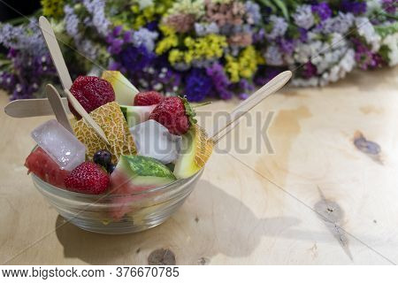 Summer Fruit Salad With Ice In A Glass Plate. Multi-colored Fruits And Berries On A Wooden Backgroun