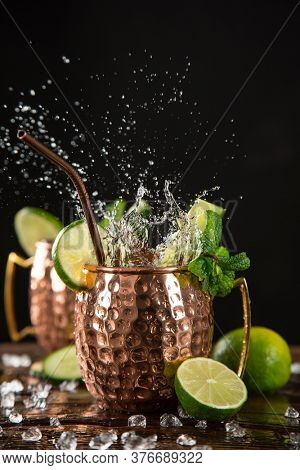 Famous splashing Moscow mule alcoholic cocktail in copper mugs, freeze motion effect.