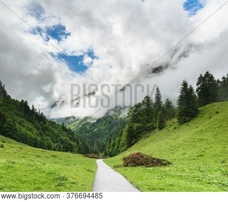 A Walking Trail Surrounded By Lush Green Alpine Mountains On A Cloudy Day In Oberstdorf, Germany