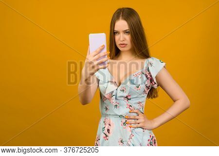 Young Woman Wears In Sunner Dress With Flowers Surprised By The News On A Smartphone - Image
