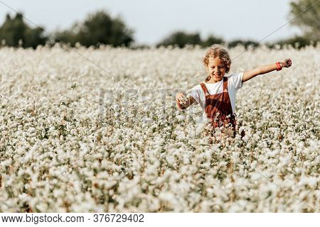 Beautiful Girl Laughs And Dances Outdoors In A Meadow During Sunset.  Livestyle Walking Concept.