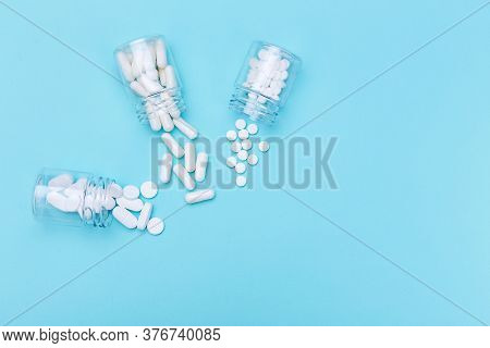 Three Packages With Various White Pills And Capcules On A Blue Background. Health Concept. Copy Spac