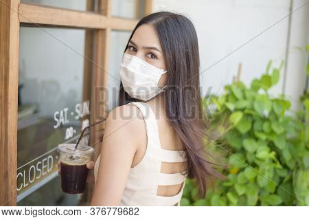 Beautiful Woman With Face Mask Is Holding Coffee In Front Of Coffee Shop