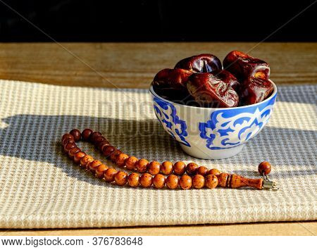 Cup With A Traditional Oriental Pattern With Dates And Stone Rosary On A Napkin During Sunset. The F