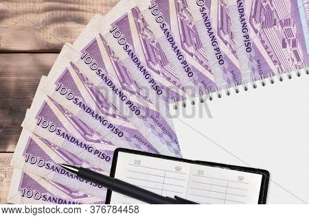 100 Philippine Piso Bills Fan And Notepad With Contact Book And Black Pen. Concept Of Financial Plan