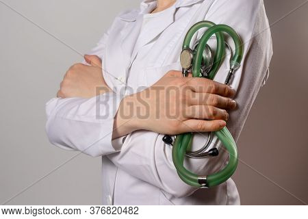 Green Stethoscope. A Doctor In A White Medical Uniform And Gloves Holds A Stethophonendoscope.