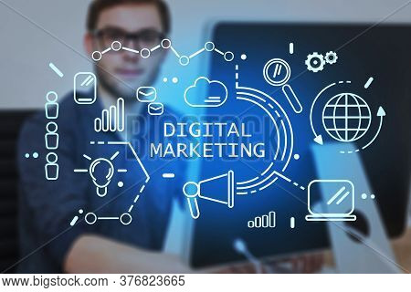 Young Businessman In Glasses Working In Blurry Office With Double Exposure Of Glowing Digital Market