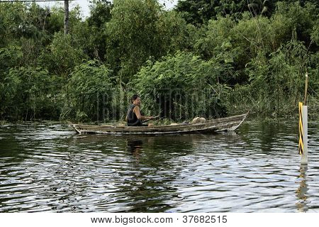 Unidentified people have to travel by boat on the road during flood