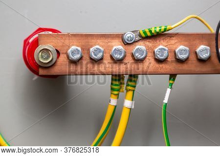 Cables Connected To A Copper Ground Bus Against A Light Wall. Horizontal Orientation.
