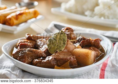 filipino pork adobo in bowl with rice in background