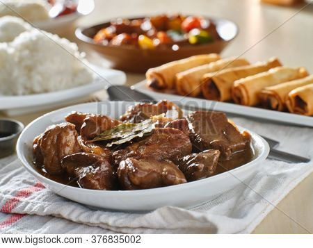 filipino pork adobo in bowl with rice in background