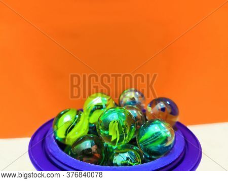 Many Green Round Marbles Arranged In Blue Pot