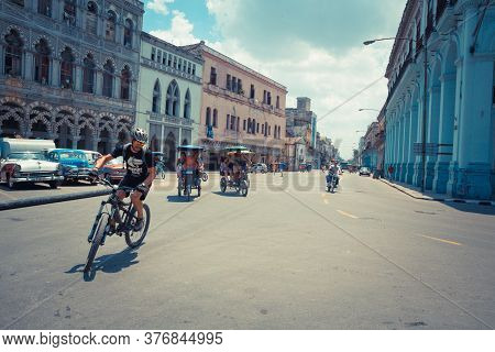 Havana / Cuba - 04.15.2015: A Biker Turning As Two Typical Cuban Bike Taxis Aka Bicitaxi Are Biking 