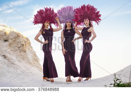 Three Beautiful Girls Poses On A Rock In Carnival Costumes