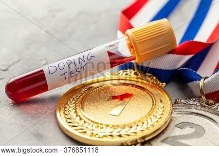Doping Test. Gold, Silver And Bronze Medal And Test Tube With Blood On A Gray Background