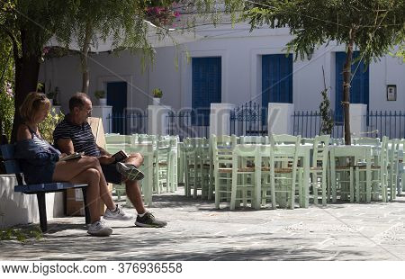 Folegandros, Cyclades / Greece / September 16 2019 : Late Afternoon In A Sunlit Square.  Two Tourist