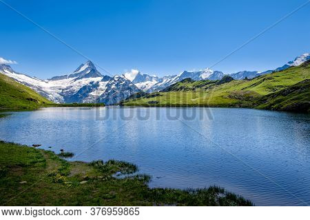 Picturesque View Of Mountain Lake Bachalpsee With The Snow Capped Peaks Of Wetterhorn, Schreckhorn A