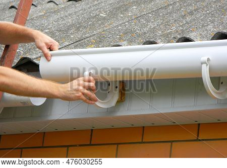 Rain Gutter Installation. Repair And Renovate Rain Gutter Pipeline On Old House With Asbestos Roofto