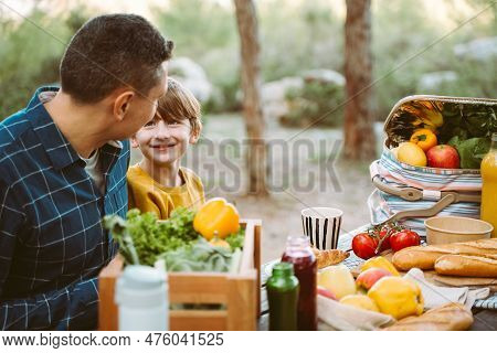 Father Hugs His School Boy Son On A Family Picnic In Mountains Forest Park. Child Kid And His Dad Ta