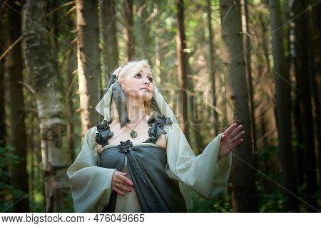 Adult Mature Woman 40-60 In A Green Long Fairy Dress In Forest. Photo Shoot In Style Of Dryad And Qu