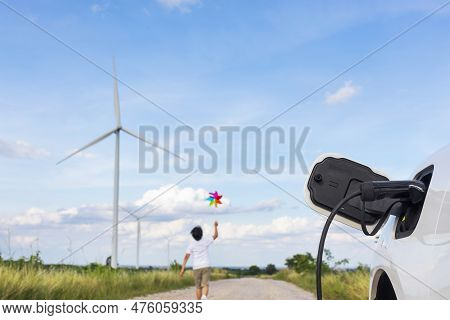 Progressive Young Asian Boy Playing With Wind Pinwheel Toy In The Wind Turbine Farm, Green Field Ove