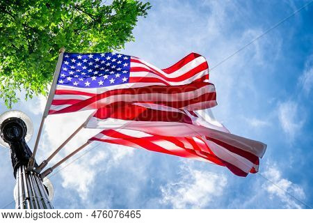 Three American Flags Hanging From A Lightweight Pole Wave In The Breeze. Bottom View Looking Up. The