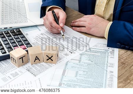 Businessman Filling W-4 Form With Pen, Calculator And Pc