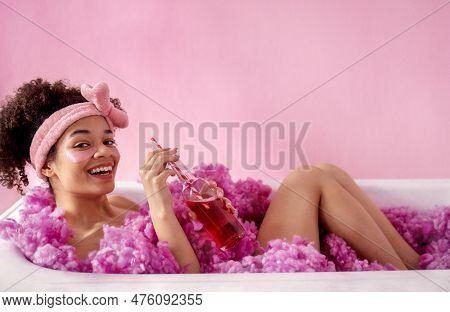 Attractive Young Female African With Terry Headband And Patches Under Her Eyes Is Sitting In Bath On