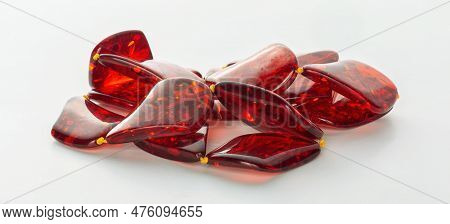 Transparent Polished Beads Of Red Amber On A White Background. Sun Stone. Natural Mineral Material F