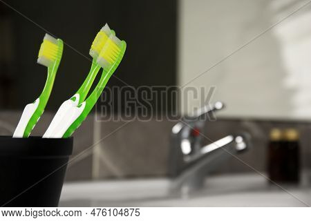 Light Green Toothbrushes In Black Toothbrush Holder Indoors, Space For Text