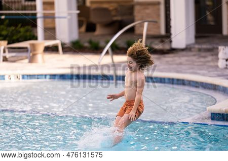 Kid Jumping In Swim Pool. Kid Enjoying Summer Holiday, Swiming In Pool. Kid Having Fun On Summer Hol
