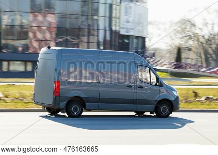 A Gray Van Drives Down The Street. A Moving Cargo Minibus. Cargo Transportation, Commercial Transpor