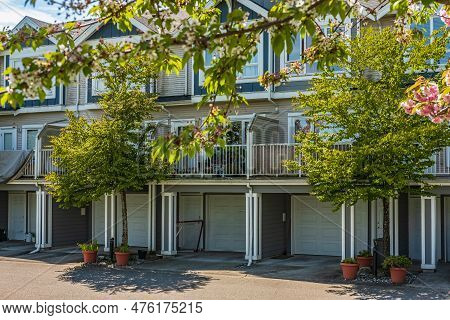 Nice Neighborhood On A Sunny Day. Row Of Garage Doors At Parking Area For Townhouses.garage Door Wit