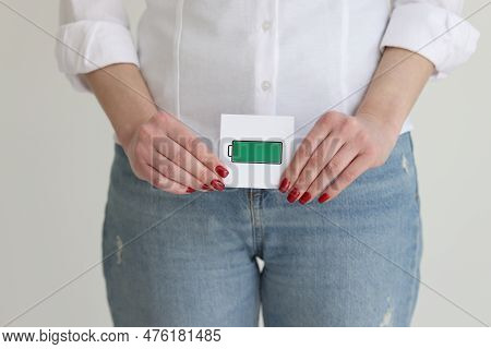 Woman In Jeans And White Shirt Holds Charged Battery Cell Picture In Studio. Healthy Libido And Life