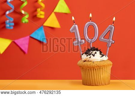 Birthday Cake With Number 104 Candle - Sparkling Orange Background With Bunting
