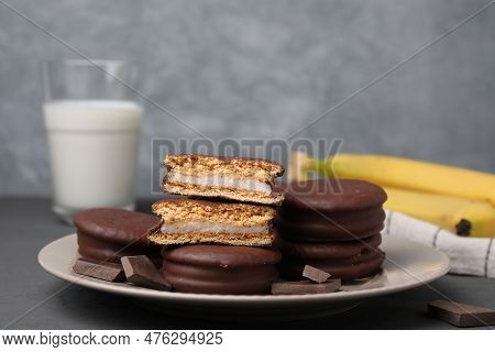 Plate With Tasty Banana Choco Pies And Pieces Of Chocolate On Grey Table, Closeup. Space For Text