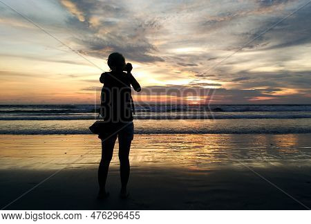 Silhouette Of A Woman On The Beach Enjoying The Sunset At Seminyak Beach.