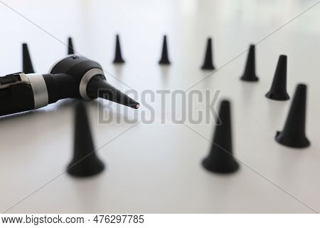 Otoscope For Ear Examination Surrounded By Black Funnels On White Table In Clinic. Professional Medi