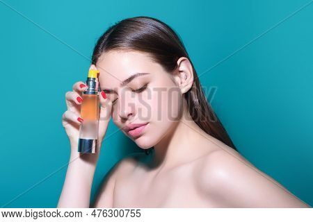 Young Pretty Woman Smelling Perfume. Sensual Woman With Bottle Of Perfume, Beauty Portrait. Female P