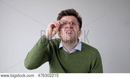 European Young Man With Poor Vision Peers Through His Glasses, Trying To Discern The Information Tha