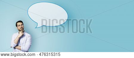 Attractive Young European Businessman With Speech Bubble On Wide Blue Background. Opinion, Speech An