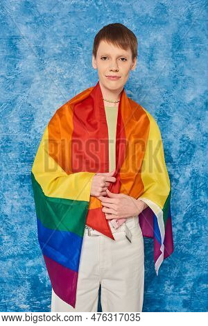Portrait Of Young Queer Person Wrapped In Lgbt Flag Looking At Camera And Standing During Pride Mont